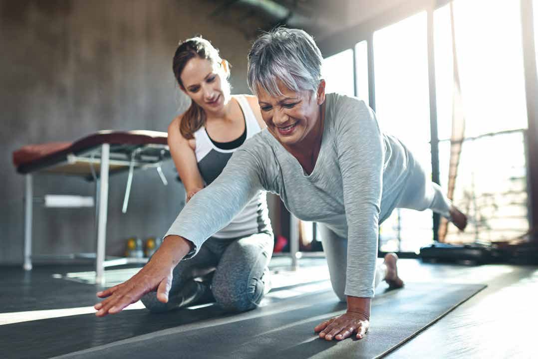 Therapist guiding a senior client through a floor exercise